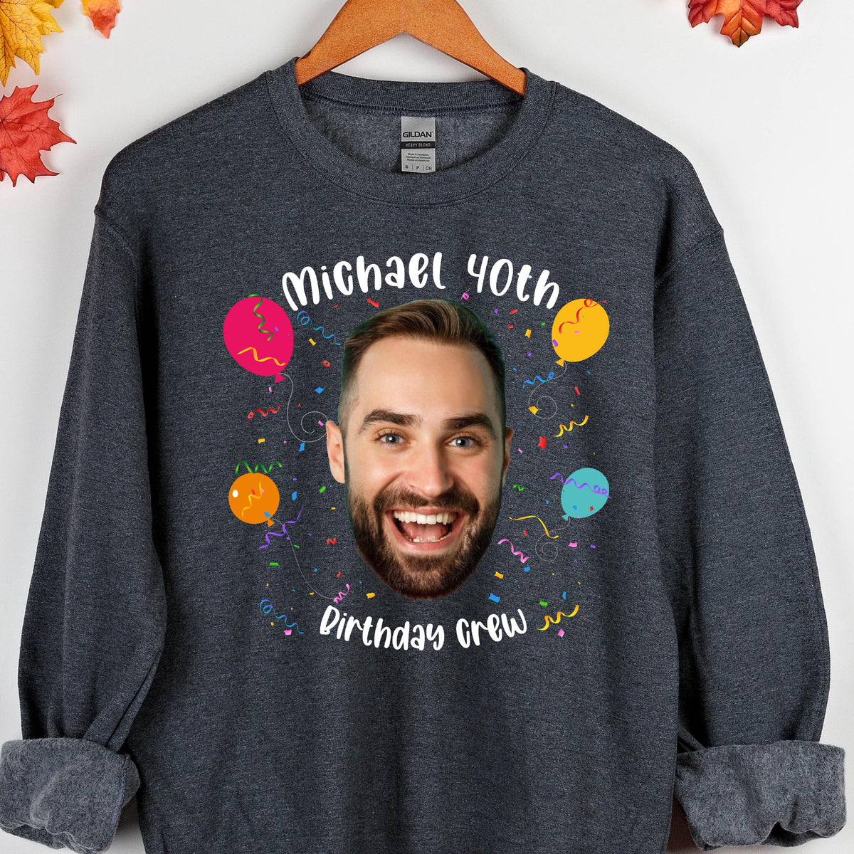 May include: A dark gray sweatshirt with a personalized design featuring a face, confetti, and balloons. The text on the sweatshirt reads "Michael 40th Birthday Crew".