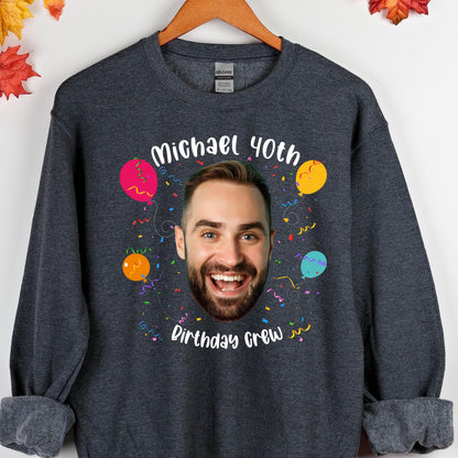 May include: A dark gray sweatshirt with a personalized design featuring a face, confetti, and balloons. The text on the sweatshirt reads "Michael 40th Birthday Crew".