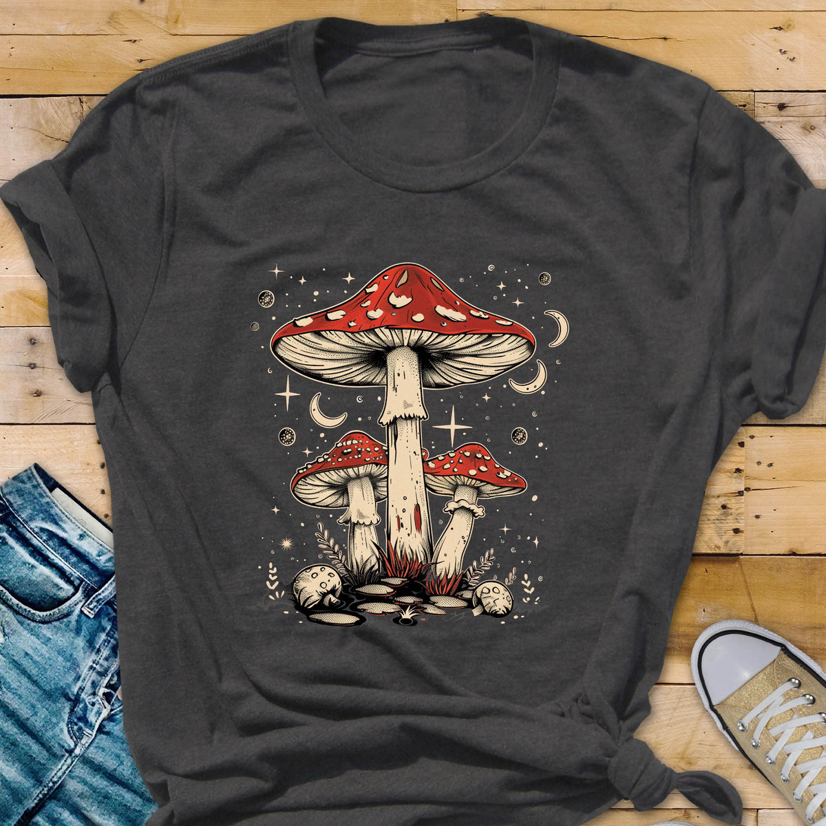 May include: A dark gray t-shirt with a graphic of three red and white mushrooms with white stems against a dark blue background with white stars and moons.