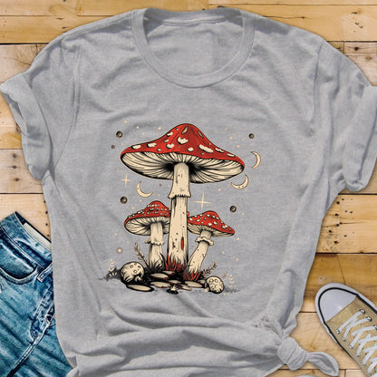 May include: A gray t-shirt with a graphic of three red and white mushrooms with white stems. The mushrooms are surrounded by white stars and crescent moons.