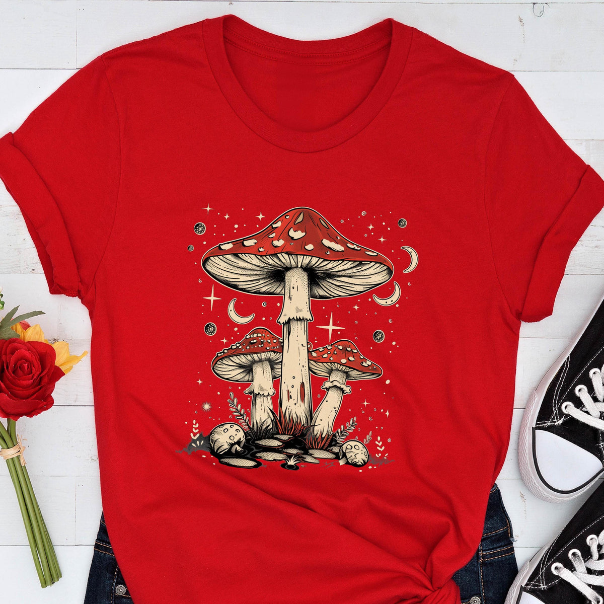May include: Red and white mushroom graphic on a red t-shirt. The mushrooms are surrounded by stars and crescent moons.