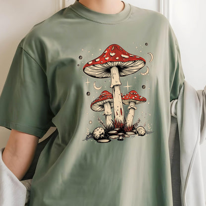 May include: A green t-shirt with a graphic of three red and white mushrooms with white spots. The mushrooms are surrounded by white stars and crescent moons.
