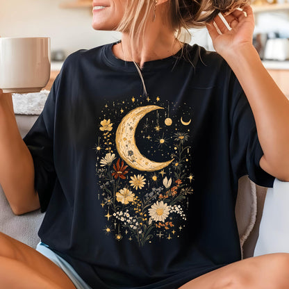May include: Black t-shirt with a crescent moon and floral design. The moon is yellow and the flowers are in shades of yellow, orange, and red. The design is surrounded by small stars.