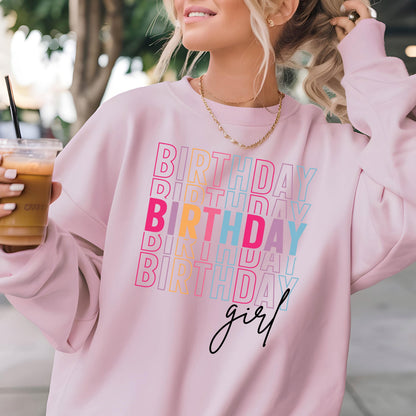 May include: Pink sweatshirt with the text "Birthday girl" in rainbow colors. The text is repeated multiple times in a stacked pattern.