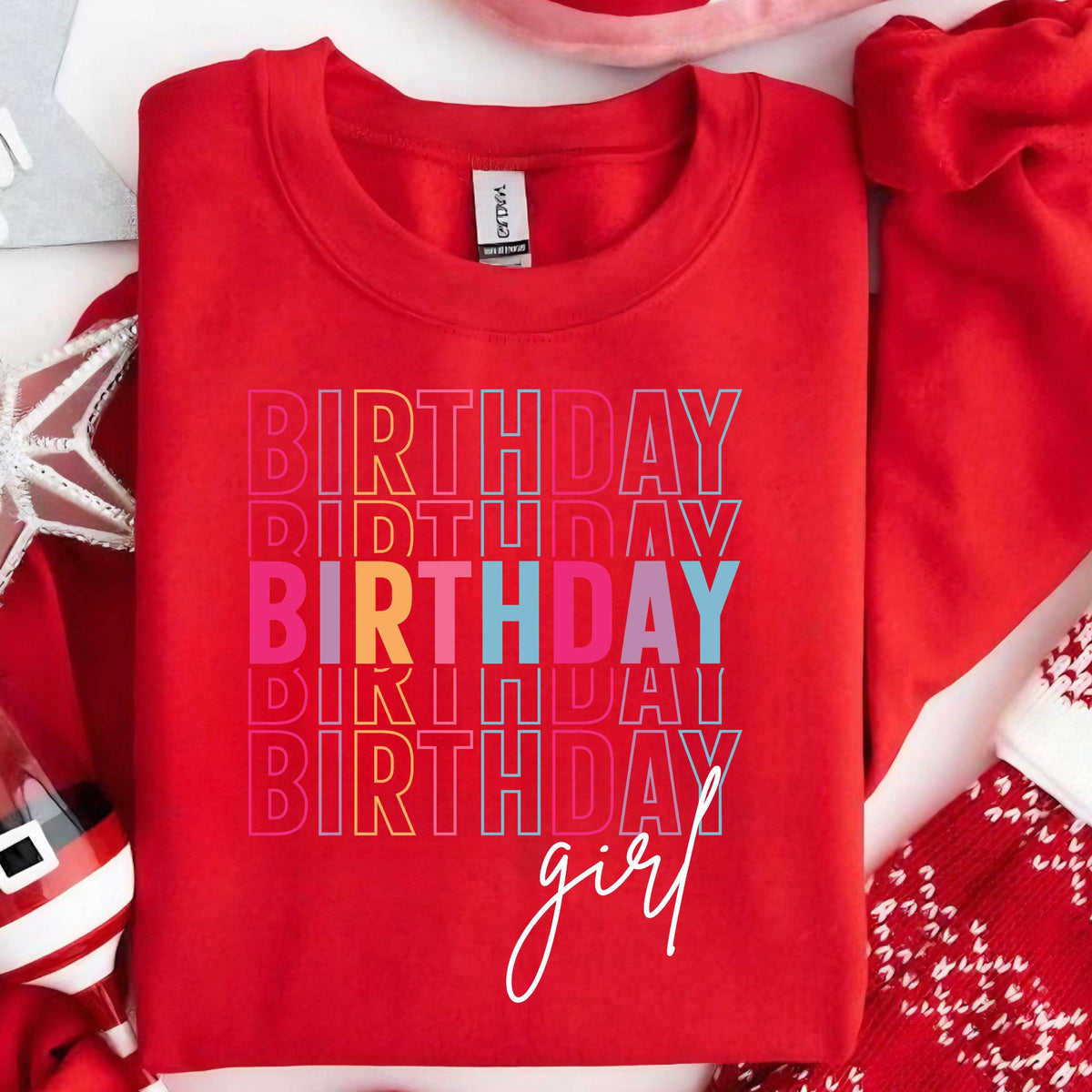 May include: Red sweatshirt with the text "Birthday girl" in rainbow colors. The text is stacked and repeated multiple times.