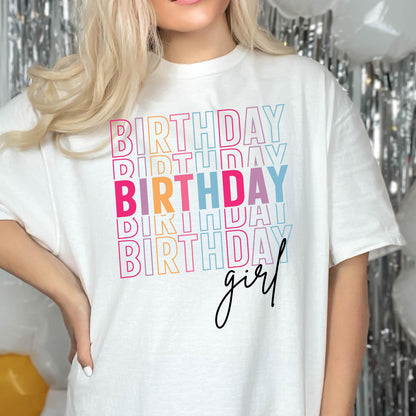 May include: White t-shirt with the text "Birthday girl" in rainbow colors. The word "Birthday" is repeated multiple times in a stacked design.