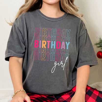 May include: A charcoal gray t-shirt with a stacked rainbow design that reads "Birthday girl".