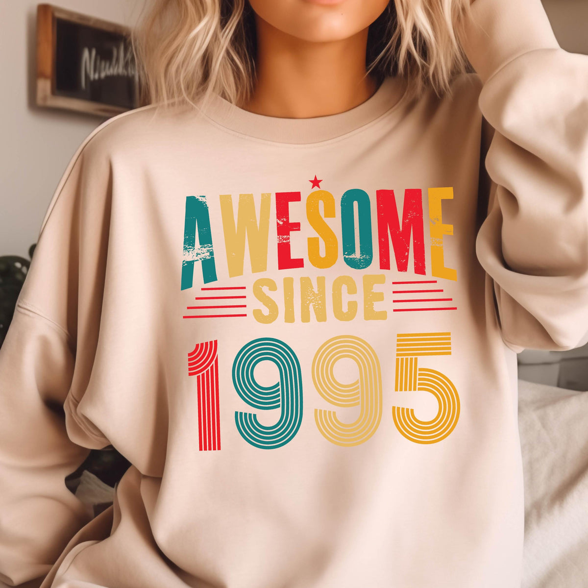 May include: A beige sweatshirt with the text "AWESOME SINCE 1995" in colorful retro-style lettering.