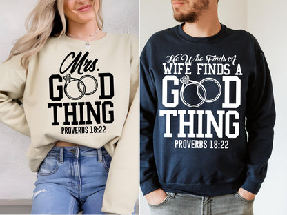 May include: Two sweatshirts, one cream-colored and one navy blue, each with a graphic design. The cream sweatshirt says "Mrs. GOOD THING" with two rings and "PROVERBS 18:22". The navy sweatshirt says "He Who Finds A WIFE FINDS A GOOD THING" with rings and "PROVERBS 18:22".