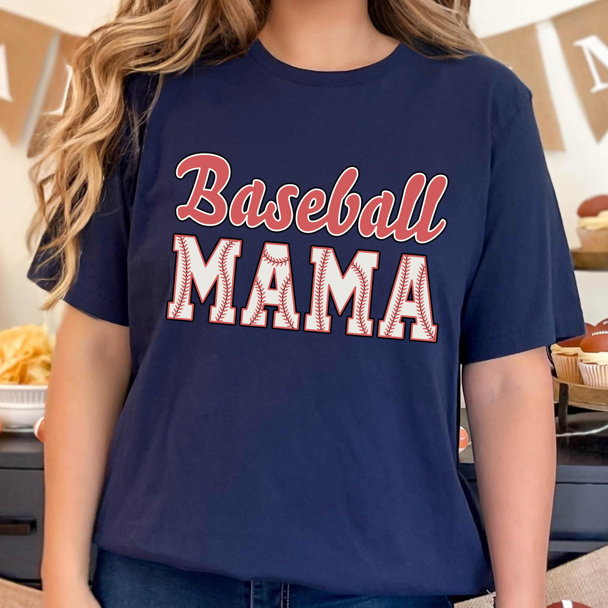 May include: A navy blue t-shirt with the text "Baseball Mama" in red and white. The letters are outlined in white and have a baseball stitch pattern.