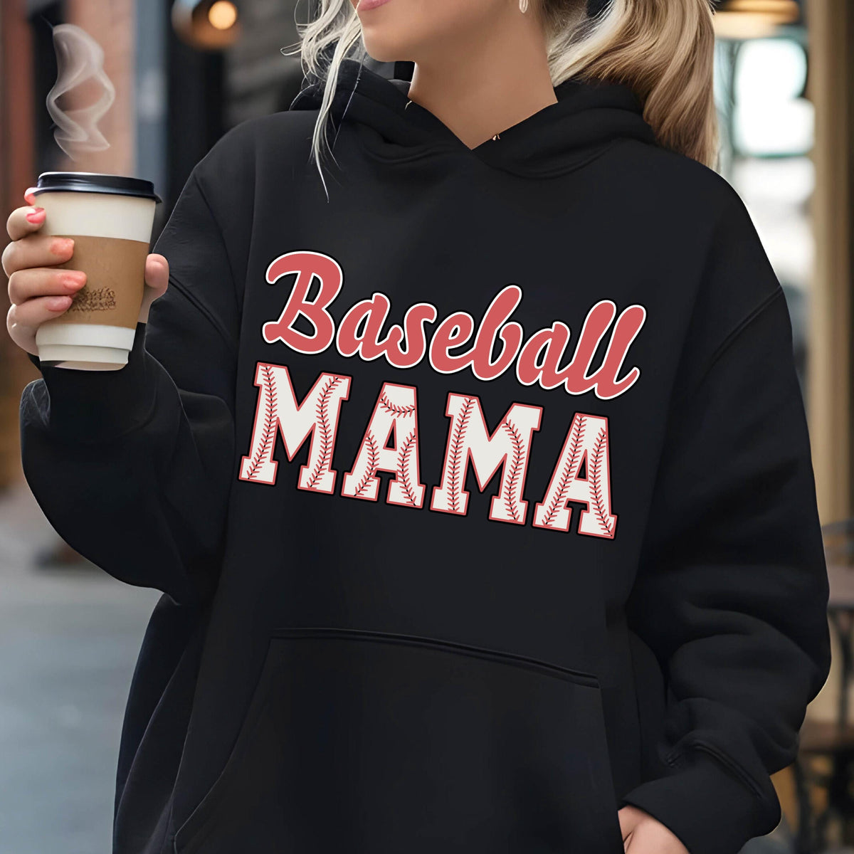 May include: A black hooded sweatshirt featuring the text Baseball MAMA printed on the front. The word Baseball is in a red script font, while the word MAMA is in large white block letters with a red baseball stitch pattern texture.