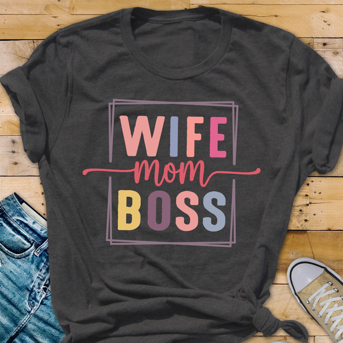 May include: Dark gray t-shirt with the words "WIFE mom BOSS" in a colorful, rectangular design. The text is in pink, blue, yellow, and purple. The shirt is made of a soft material and is suitable for casual wear.