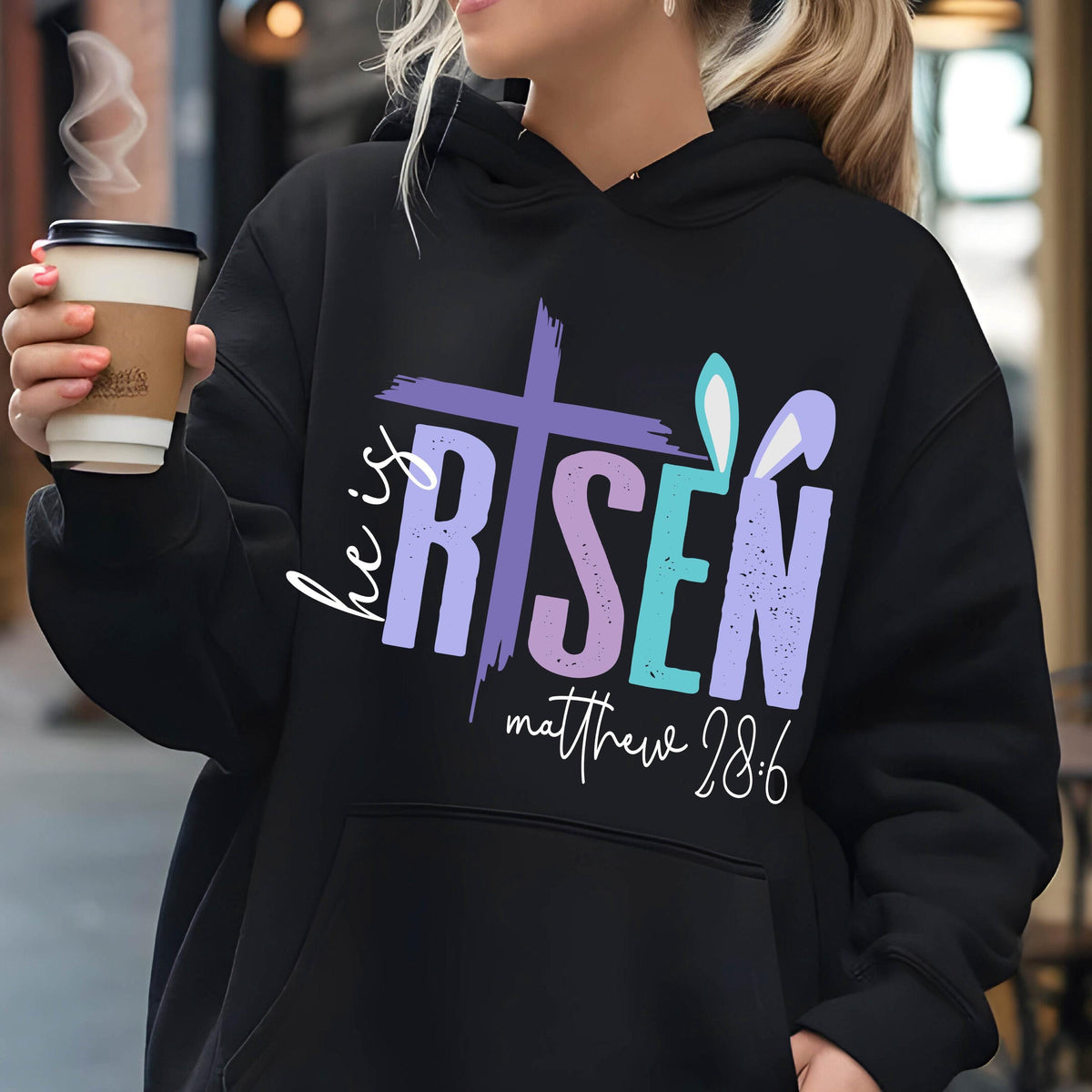 May include: Black hoodie with a purple, blue, and pink graphic that says "He is Risen" with a cross and bunny ears. The text "Matthew 28:6" is below the graphic.