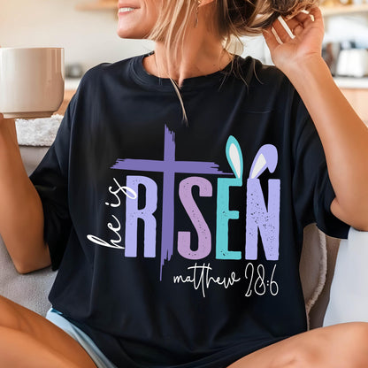 May include: Black t-shirt with a colorful graphic that says "He is Risen" with a cross and bunny ears. The text "Matthew 28:6" is below the graphic.