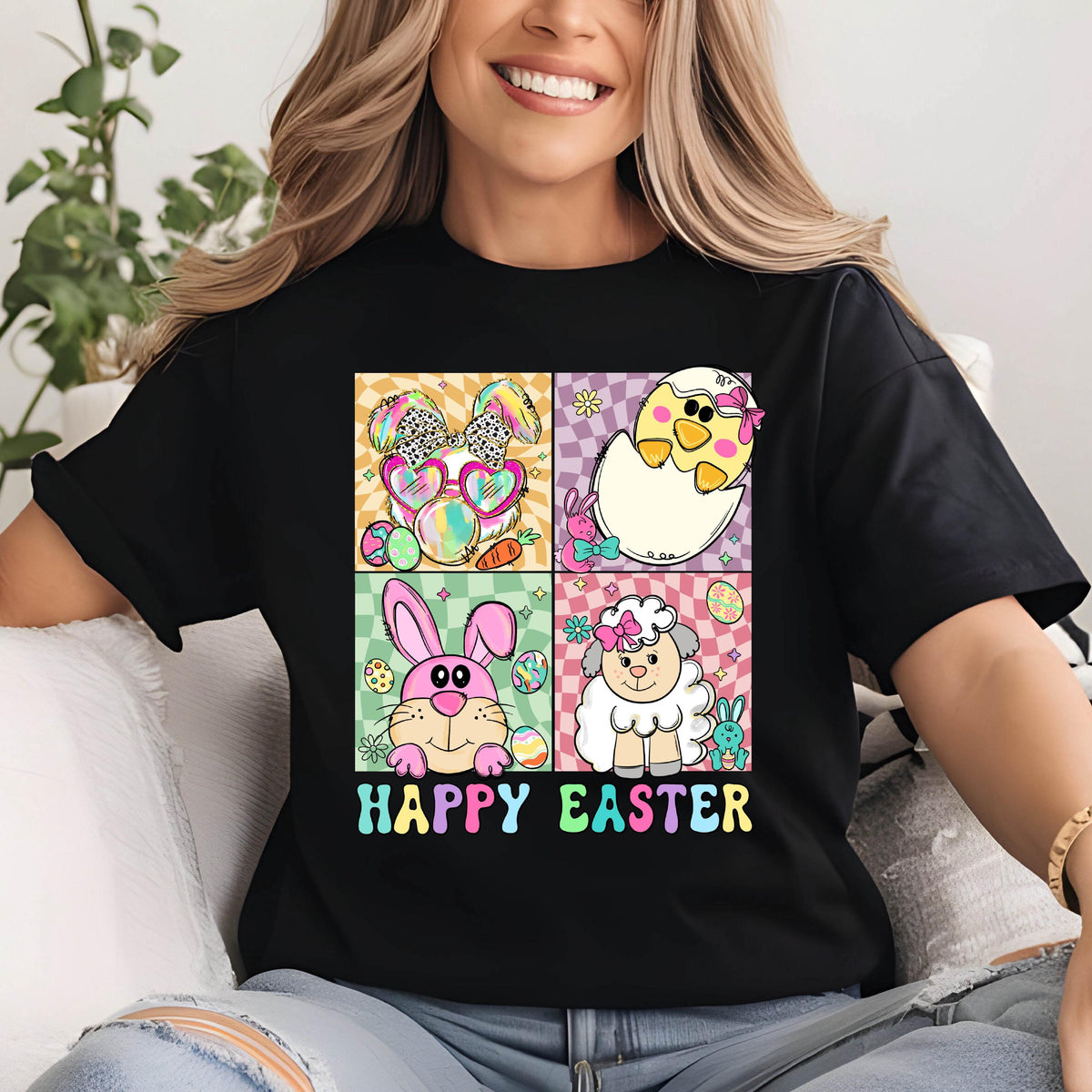 May include: Black t-shirt with a colorful "Happy Easter" graphic. The graphic features four squares with Easter-themed illustrations: a bunny with sunglasses, a chick hatching from an egg, a pink bunny, and a sheep.