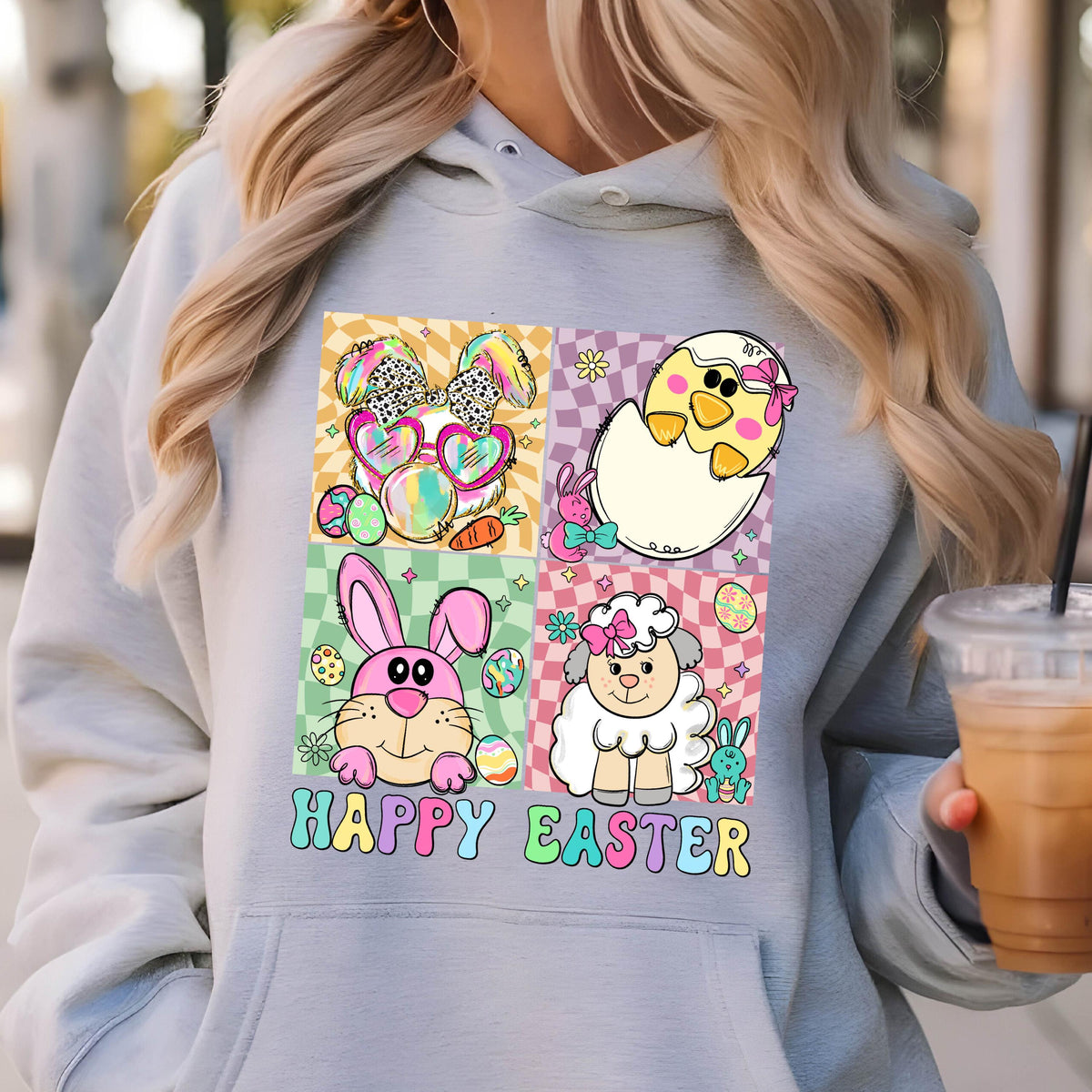 May include: A light gray hoodie with a colorful graphic of a bunny, chick, and lamb. The graphic is surrounded by a checkered pattern and the text "Happy Easter" is printed below.