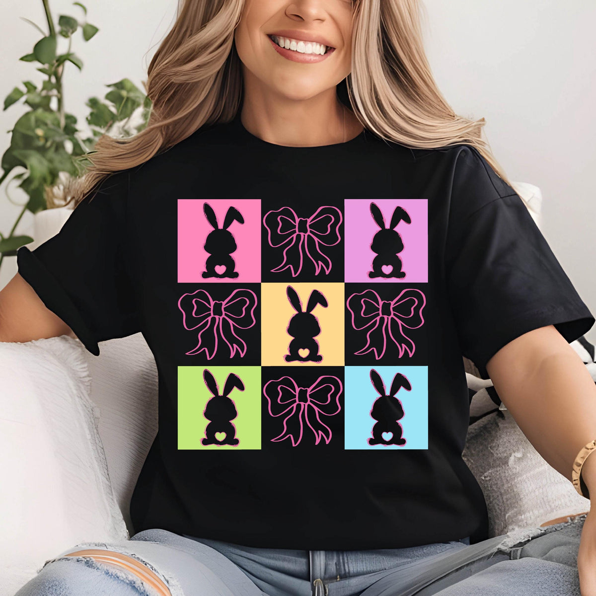 May include: Black t-shirt with a colorful design of bunnies with bows. The bunnies are in a grid pattern with each bunny in a different colored square. The bows are pink.