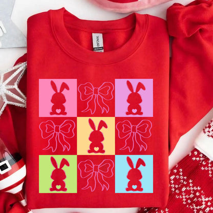 May include: Red sweatshirt with a graphic design of nine squares. Each square features a pink bunny with a heart and a pink bow. The squares are arranged in a 3x3 grid and are in different colors: pink, yellow, light blue, and green.
