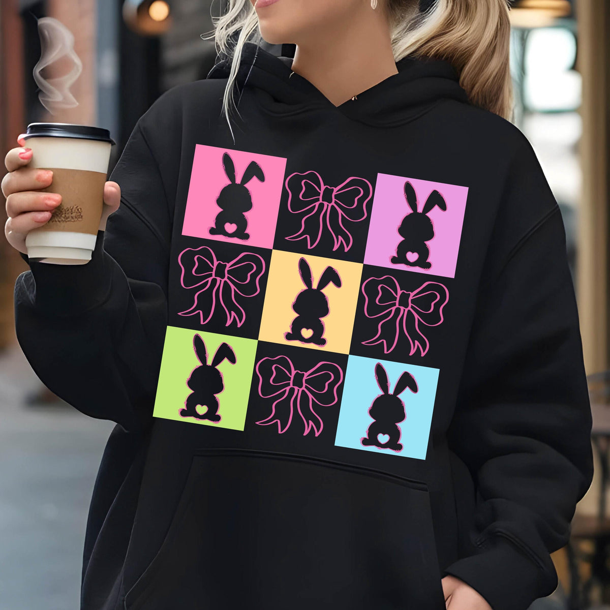 May include: Black hoodie with a colorful design of bunnies and bows. The design is in a grid pattern with each square having a different color.
