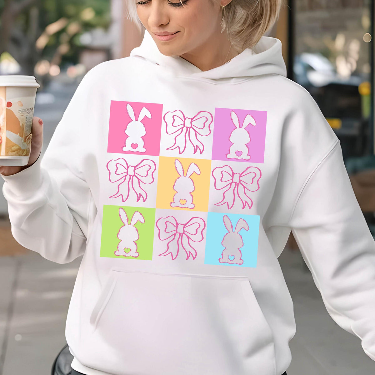 May include: White hoodie with a colorful graphic of bunnies and bows. The graphic is made up of nine squares, each with a different color and design.