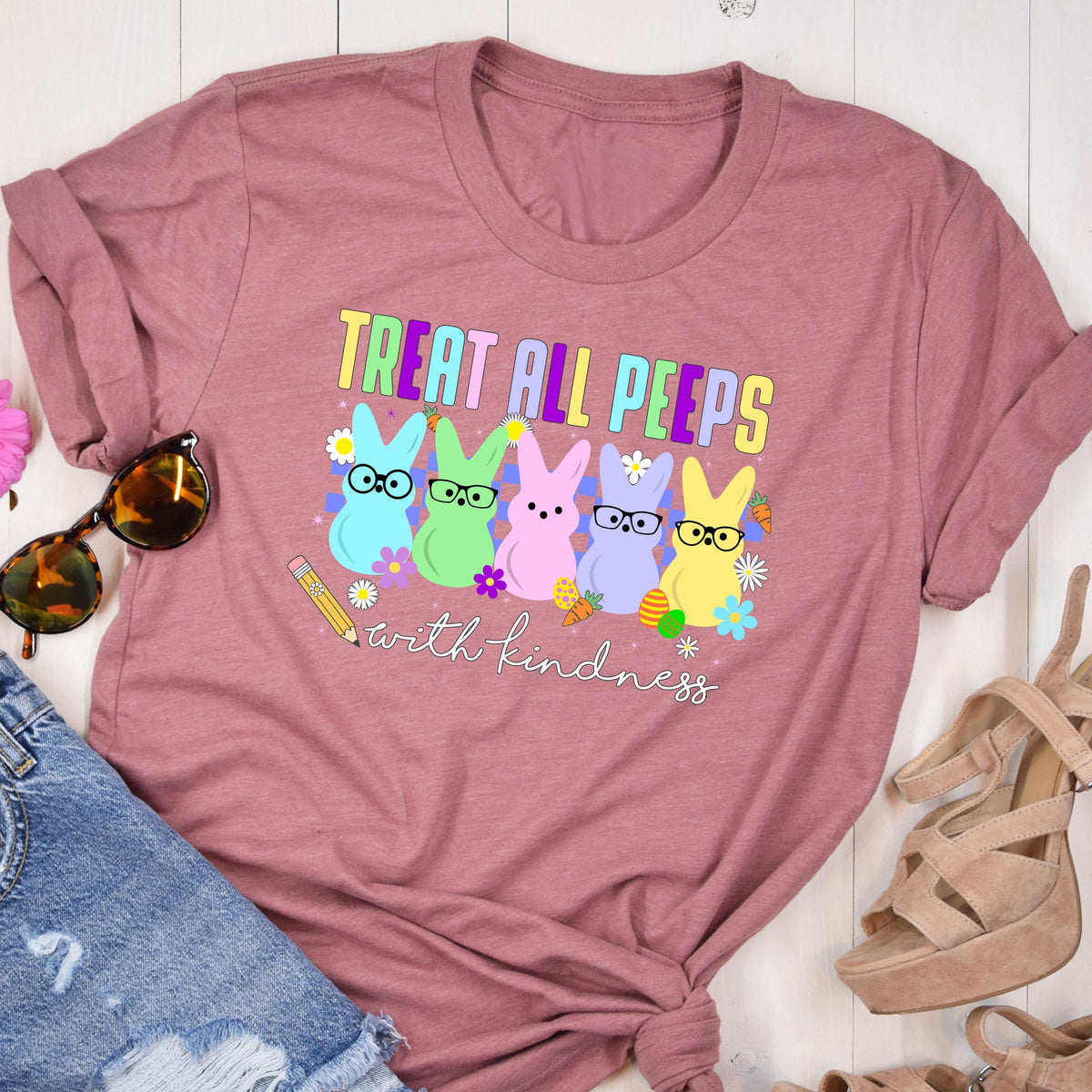 May include: A pink t-shirt with the text "Treat all peeps with kindness" and a graphic of four pastel-colored peeps wearing glasses. 