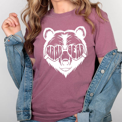 May include: A mauve t-shirt with a white graphic of a bear wearing heart-shaped sunglasses that say "Mama Bear".