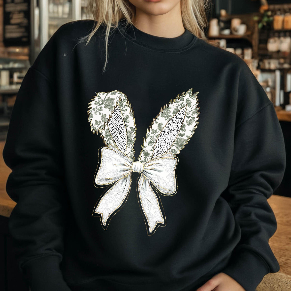 May include: Black sweatshirt with a white and gold embroidered design of a bow with bunny ears.