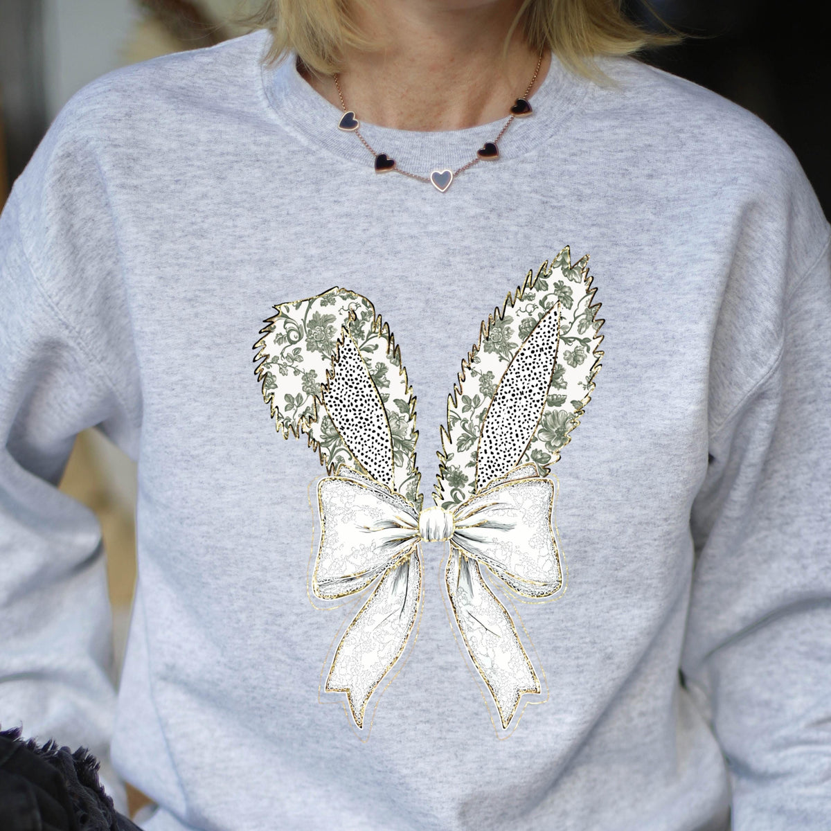 May include: A gray sweatshirt with a white and green bunny rabbit design. The bunny has a large bow tied around its neck.