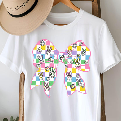 May include: White t-shirt with a pink bow featuring a checkered pattern with bunny faces and flowers.