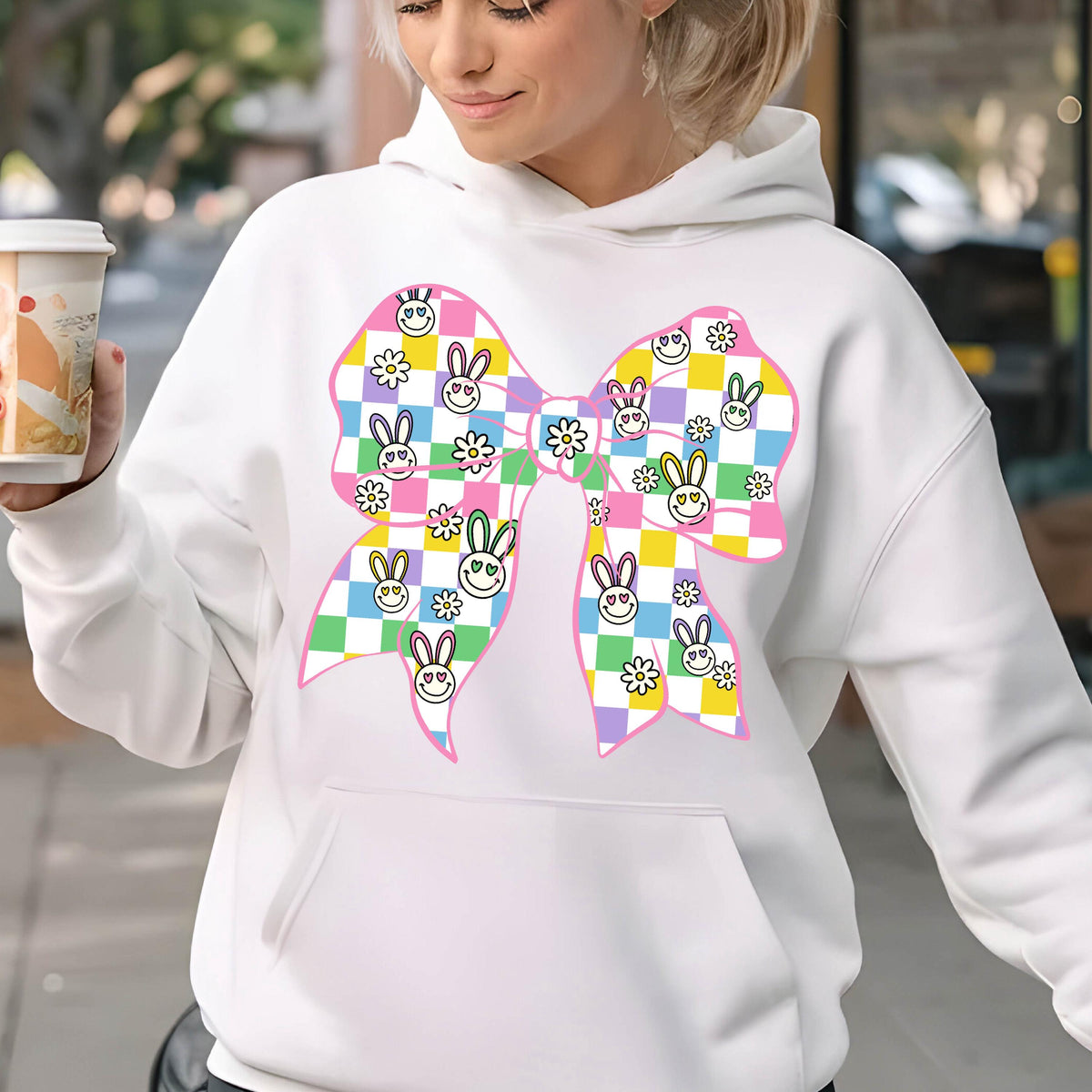 May include: White hoodie with a pink bow featuring a checkered pattern with bunny faces and flowers. 