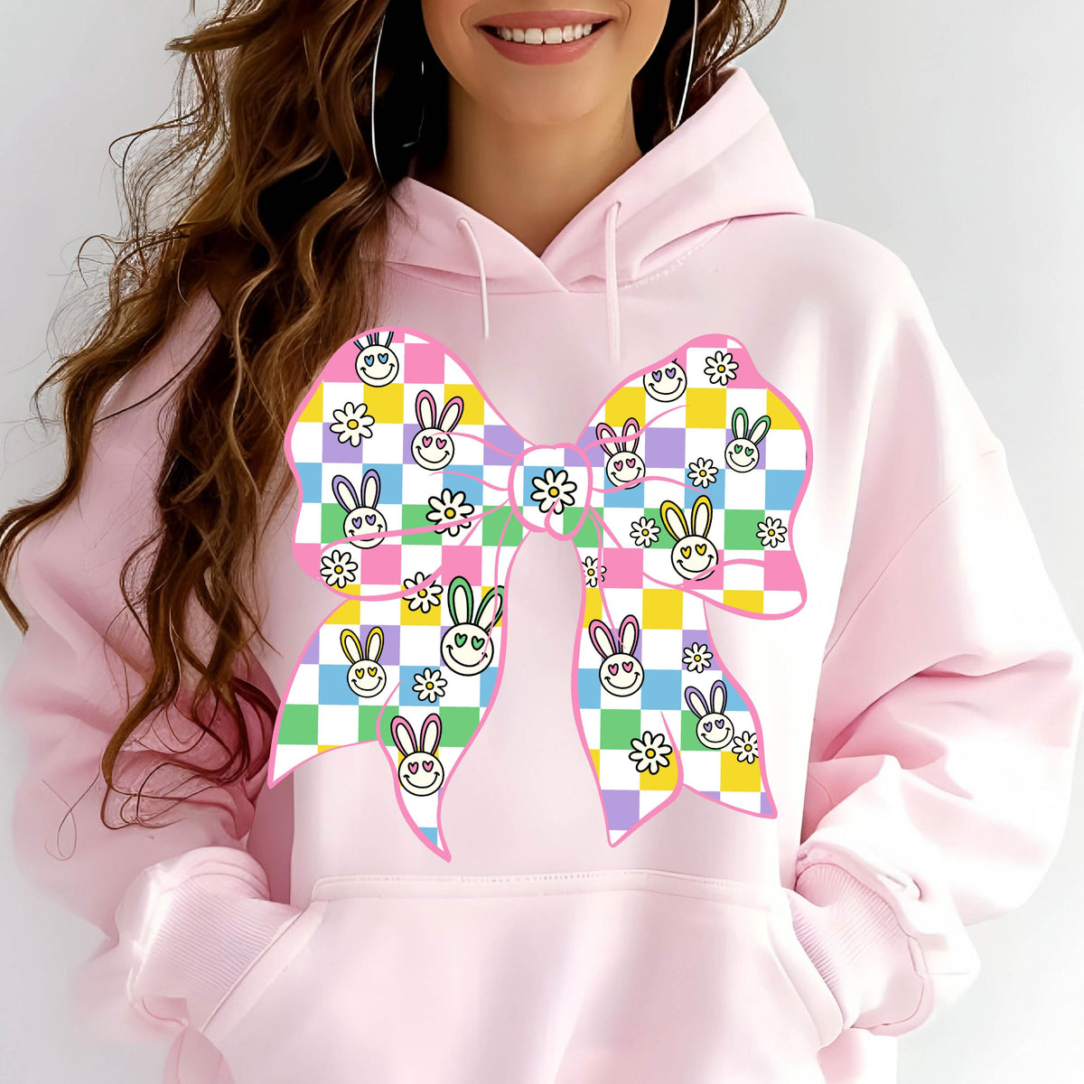 May include: Pink hoodie with a large checkered bow featuring bunny and flower designs. The bow is in shades of pink, yellow, green, and blue.