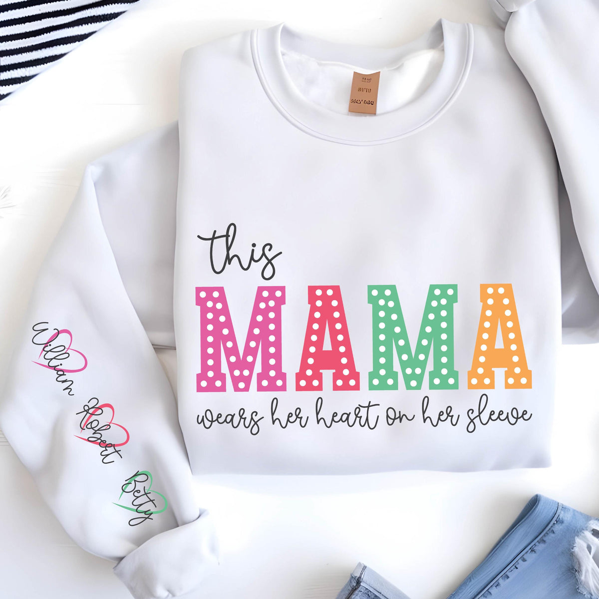 May include: White sweatshirt with the text "this mama wears her heart on her sleeve" in colorful letters with white polka dots. The sleeve has the names "William, Robert, Betty" written in a heart shape.