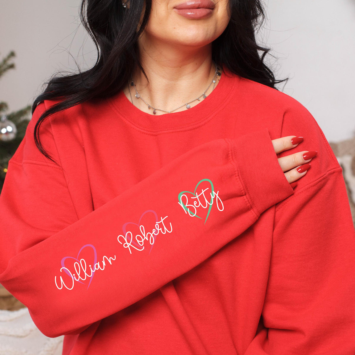 May include: Red sweatshirt with a long sleeve featuring the names "William Robert" and "Betty" written in cursive with hearts around them.