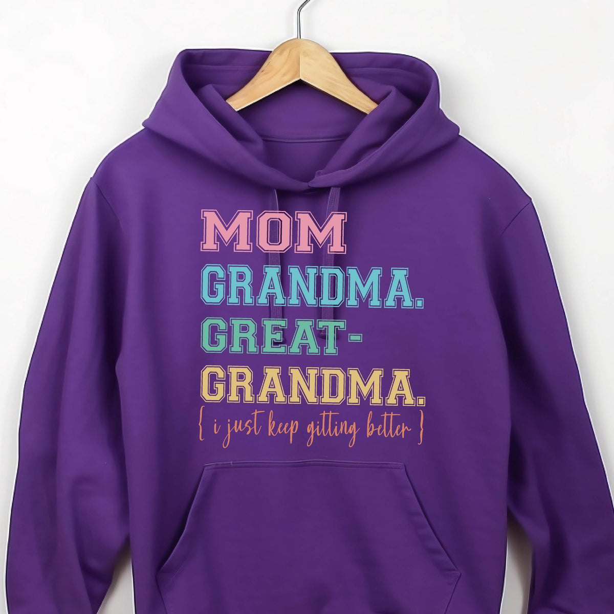 May include: Purple hoodie with the text "MOM GRANDMA. GREAT-GRANDMA. I just keep getting better." in rainbow colors.
