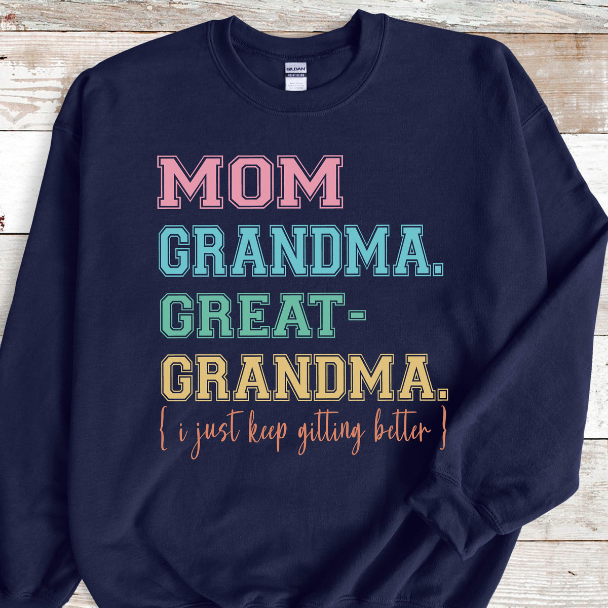 May include: Navy blue sweatshirt with the text "MOM GRANDMA. GREAT-GRANDMA. [i just keep getting better]" in colorful block letters.