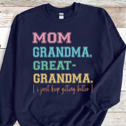 May include: Navy blue sweatshirt with the text "MOM GRANDMA. GREAT-GRANDMA. [i just keep getting better]" in colorful block letters.