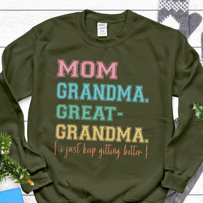 May include: Olive green sweatshirt with the text "MOM GRANDMA. GREAT-GRANDMA. [i just keep getting better]" in pink, blue, green, and yellow.