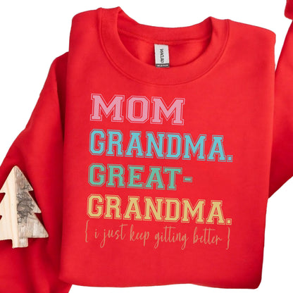 May include: Red sweatshirt with a white, pink, blue, green, and yellow graphic print that reads "MOM GRANDMA. GREAT-GRANDMA. {i just keep getting better}"