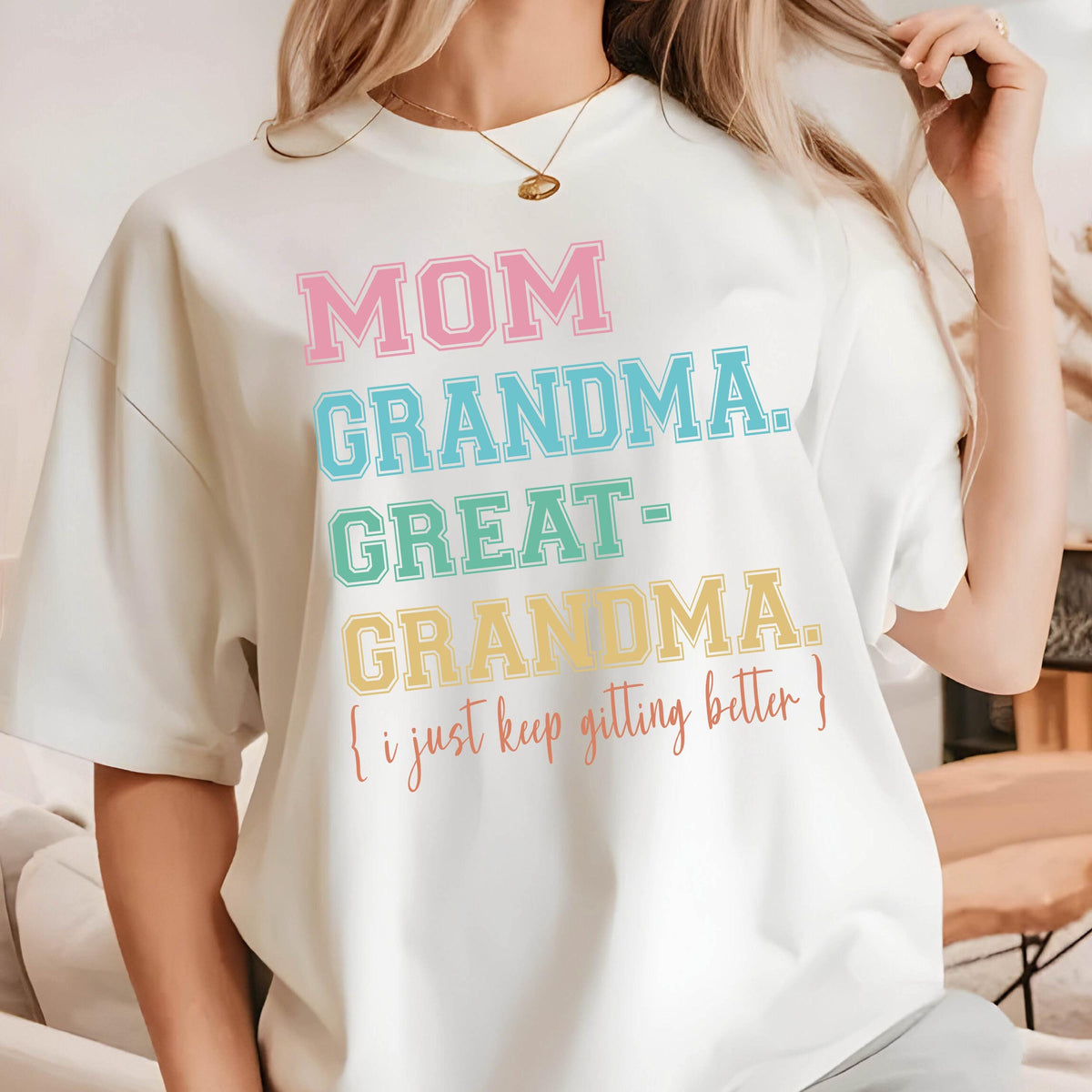 May include: White t-shirt with a colorful graphic that reads "MOM GRANDMA GREAT-GRANDMA. [i just keep getting better]"