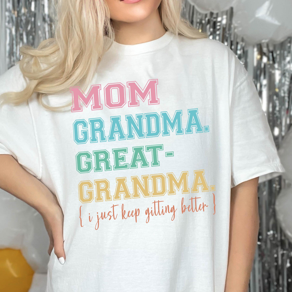 May include: White t-shirt with a rainbow colored graphic that reads "MOM GRANDMA GREAT-GRANDMA (I just keep getting better)"