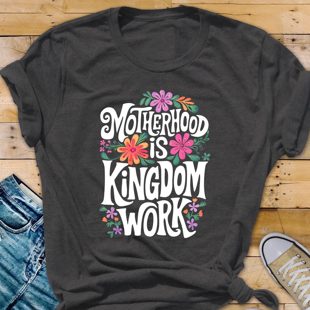May include: A dark gray t-shirt with a white graphic that says "Motherhood is Kingdom Work" surrounded by colorful flowers.