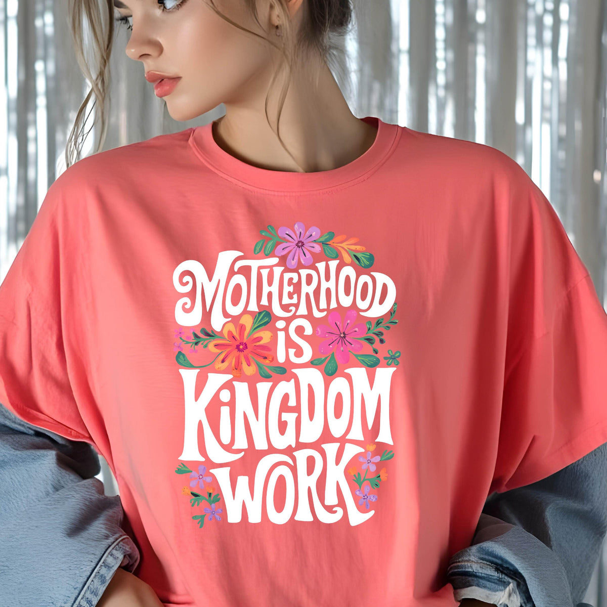 May include: A coral pink t-shirt with a white graphic that says "Motherhood is Kingdom Work" surrounded by colorful flowers.