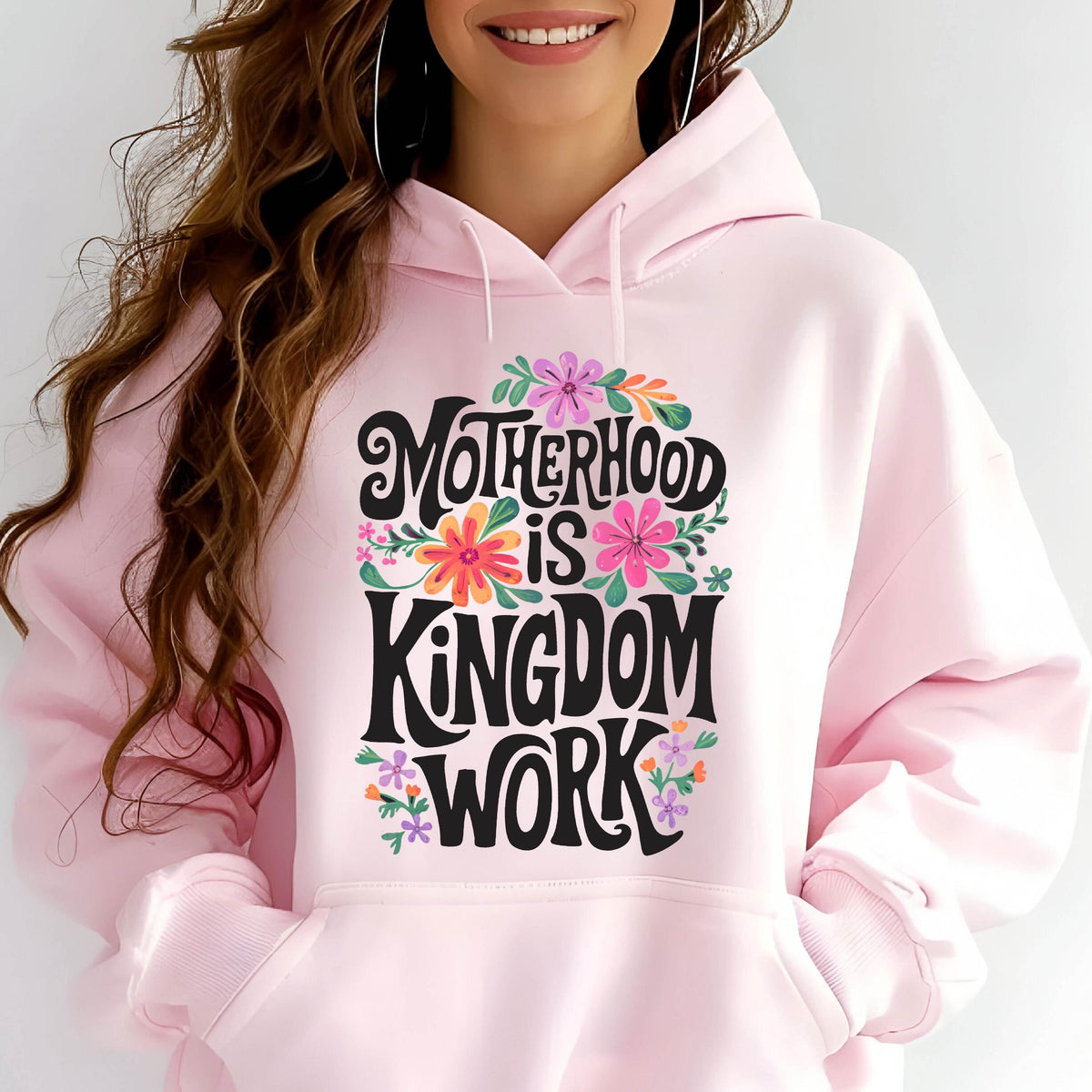 May include: Pink hoodie with a floral design and the text "Motherhood is Kingdom Work" in black lettering.