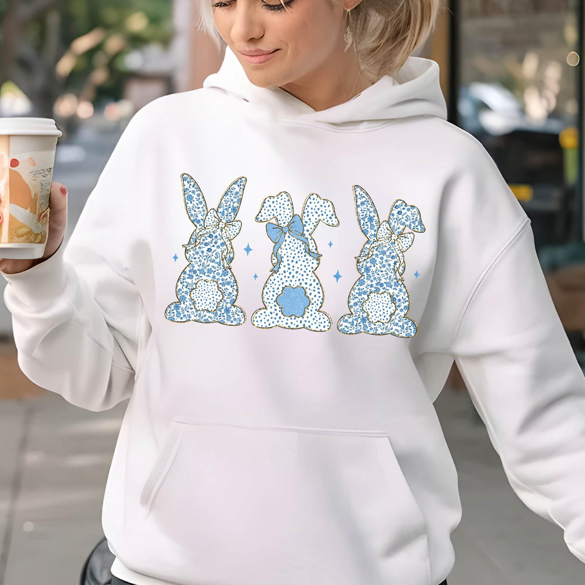 May include: White hoodie with a blue and gold bunny rabbit design. The bunnies are in a row and have bows on their heads.