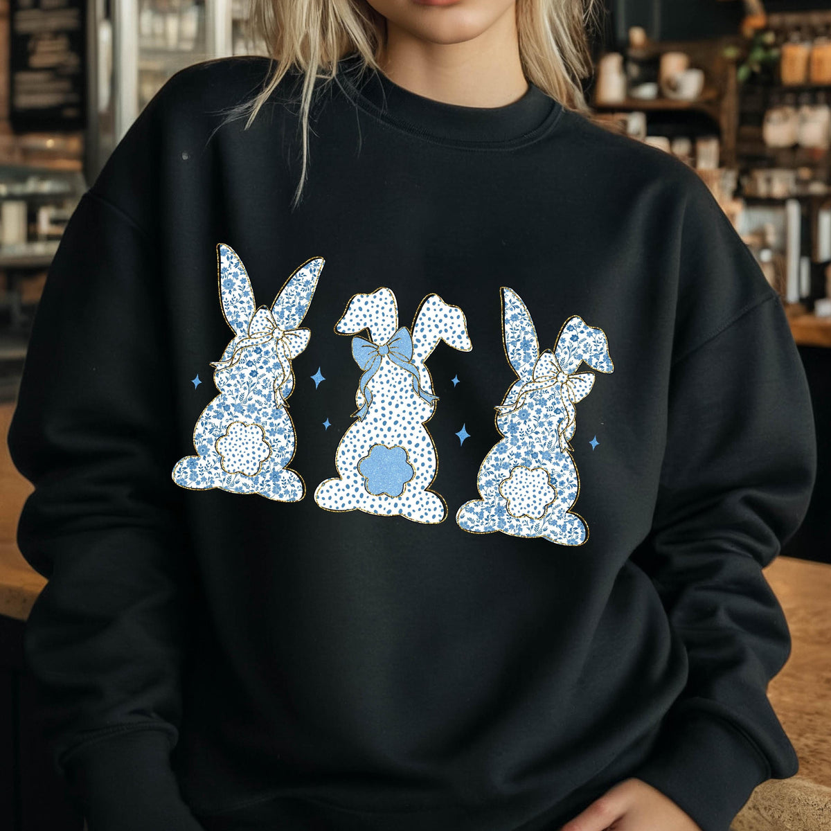 May include: Black sweatshirt with a graphic of three blue bunnies with white polka dots and blue bows. The bunnies are facing away from the viewer.