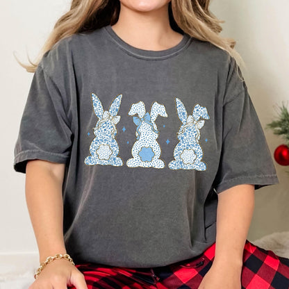 May include: A charcoal gray t-shirt with a graphic of three blue bunnies with white polka dots and blue bows. The bunnies are facing away from the viewer.