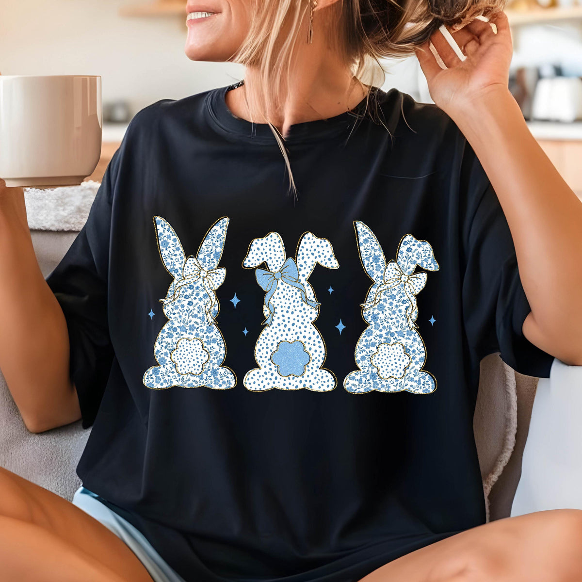May include: Black t-shirt with a graphic of three blue bunnies with white polka dots and blue bows. The bunnies are facing away from the viewer.