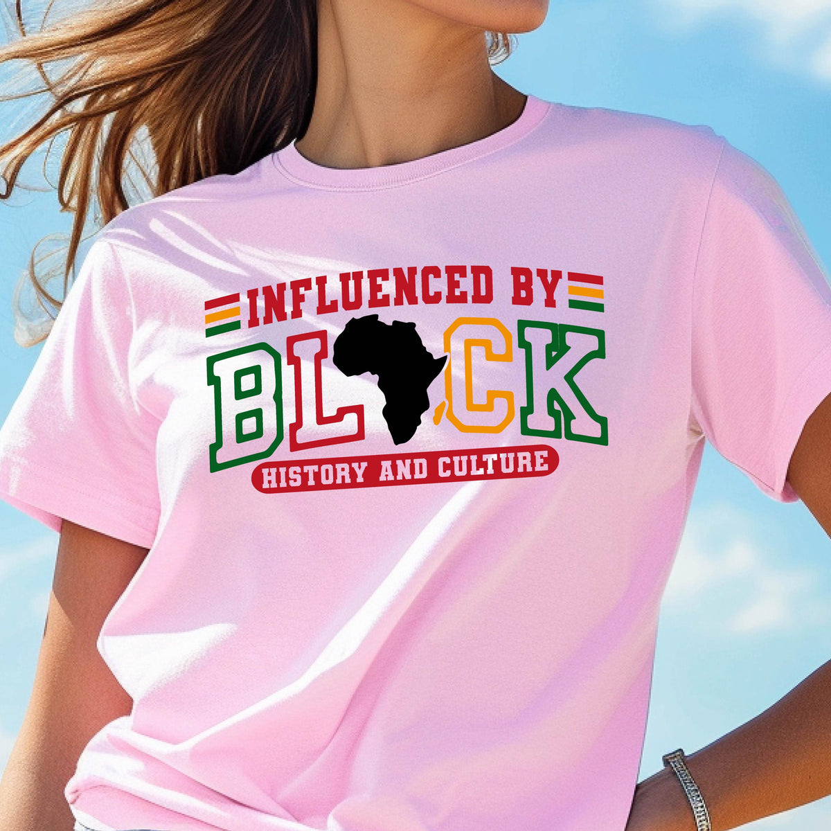 May include: A light pink short-sleeved t-shirt featuring the text INFLUENCED BY BLACK HISTORY AND CULTURE. The word BLACK is stylized with a black silhouette of the African continent replacing the letter A, with green, yellow, and red accents.