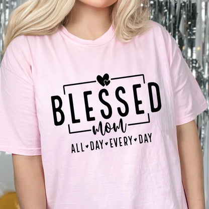 May include: Pink t-shirt with a black graphic that says "Blessed Mom All Day Every Day" with a heart symbol between each word.