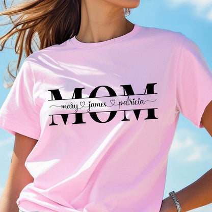 May include: Pink t-shirt with the word "MOM" in black letters. Underneath the word "MOM" is a banner with the text "mary ♥ james ♥ patricia" in black.